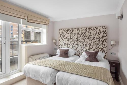 a bedroom with a large bed and a window at Beaufort House - Knightsbridge in London