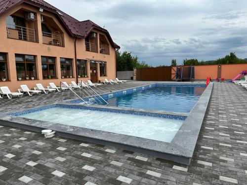 a swimming pool in front of a building at HotelVizit in Solotvyno