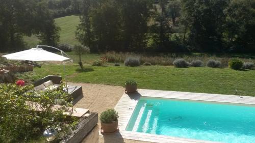 - une piscine dans un jardin avec un parasol dans l'établissement bastide de beauvallon, à Fourcès