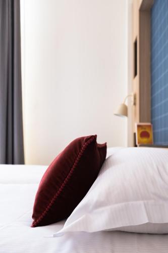 a red pillow sitting on a bed with a window at Marnie House in Le Touquet-Paris-Plage