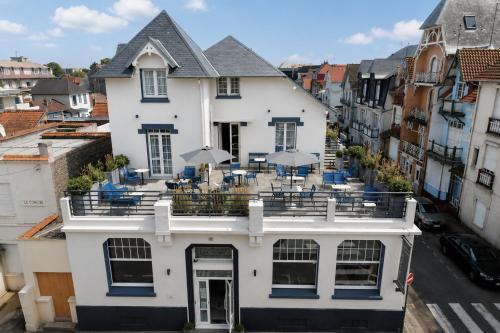 a white building with chairs and umbrellas on it at Marnie House in Le Touquet-Paris-Plage