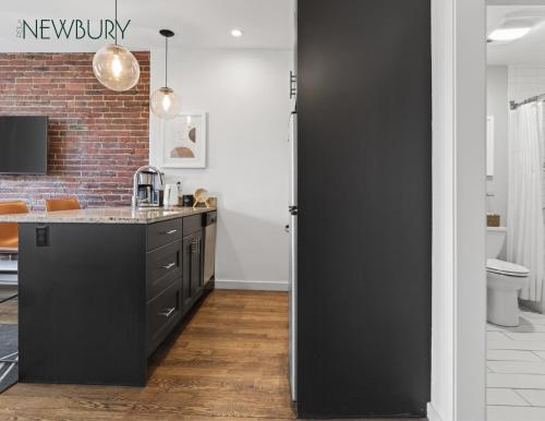 a kitchen with black cabinets and a brick wall at 304 Newbury Street by Thatch in Boston