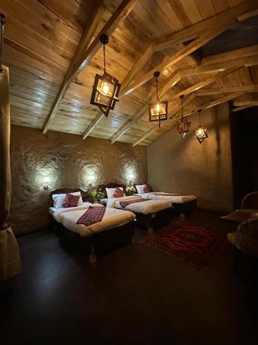 a bedroom with two beds in a room with wooden ceilings at Trivor resort in Hunza Valley