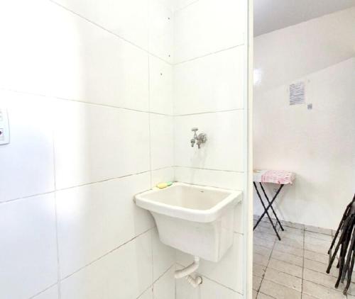 a white bathroom with a sink on the wall at Hospedagem Aeroporto in Campinas