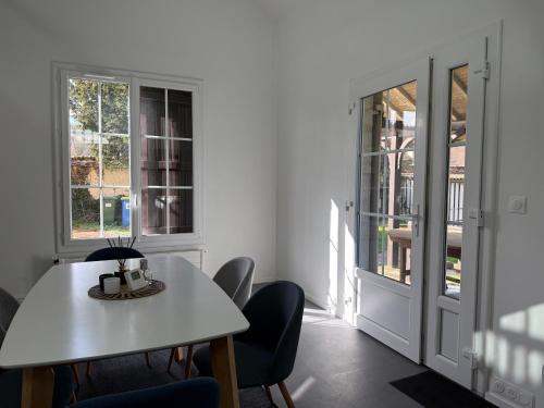 a white dining room with a table and chairs at La Maisonnette de Fontaine - Au calme avec jardin in Fontaine-sous-Jouy