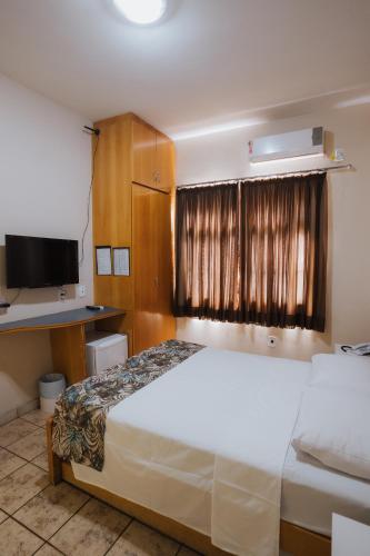 a bedroom with a white bed and a television at Hotel Nacional Service - Fácil acesso a Região da 44 e Rodoviária in Goiânia