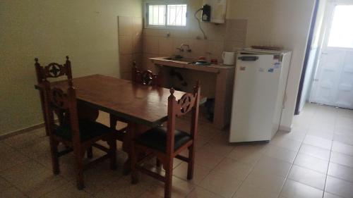 a kitchen with a wooden table and a refrigerator at ruta 8 suites in Santa Catalina
