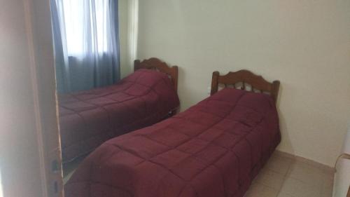 two beds in a room with pink sheets and a mirror at ruta 8 suites in Santa Catalina