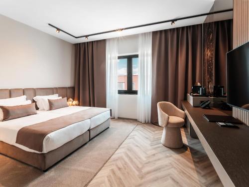 a bedroom with a bed and a desk and a television at Diaco Boutique Hotel in Đakovo