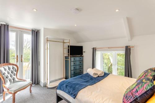 a bedroom with a bed and a chair and a television at 6 Bed in Holsworthy oc-s41430 in Merryfield