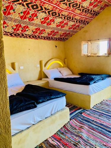 two beds sitting in a room with a rug at Fayoum Desert Camp in Qaryat Ḩātim aţ Ţāʼī