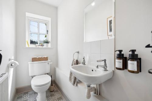 a white bathroom with a toilet and a sink at Five Acres Cottage in Rickmansworth