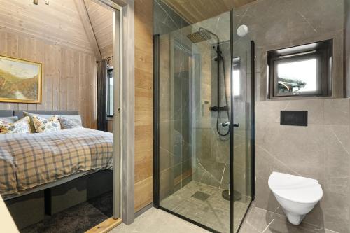 a bathroom with a shower and a toilet and a bed at Large modern cabin from 2023 for rent in Dirdal