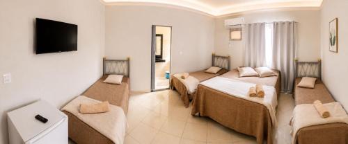 a hotel room with three beds and a flat screen tv at Hotel Eldorado de Salinas in Salinas