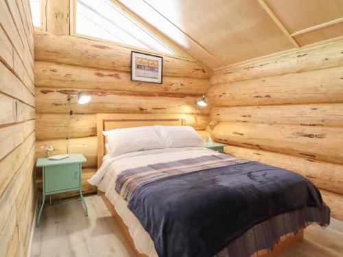 a bedroom with a bed in a log cabin at Owl Valley Cabin in Oswestry