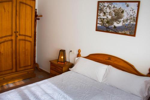 a bedroom with a bed and a picture on the wall at La flor del cerezo in Piornal