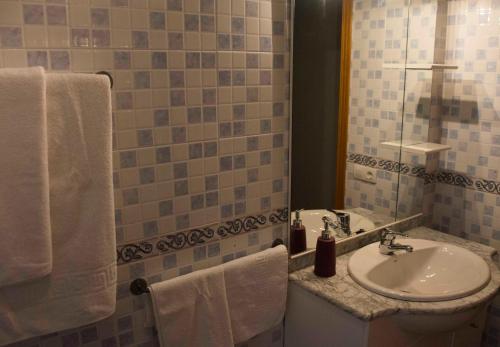 a bathroom with a sink and a mirror and towels at La flor del cerezo in Piornal