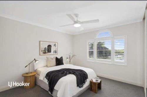 a white bedroom with a bed and a window at MawsonLakes Lake view Villa in Mawson Lakes