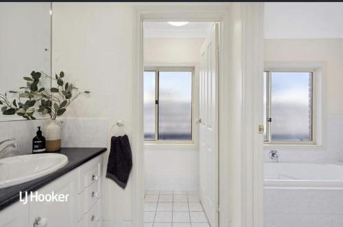 a white bathroom with a tub and a sink at MawsonLakes Lake view Villa in Mawson Lakes