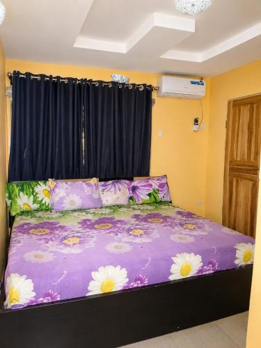 a bedroom with a purple bed with flowers on it at Tee's Place in Coker