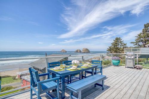 a blue table and chairs on a deck with the beach at Serendipity - Whole in Oceanside