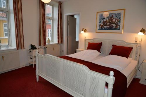 a bedroom with a large white bed with red pillows at Hotel Ærø in Svendborg