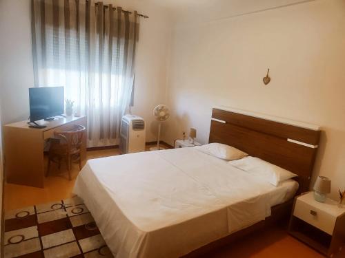 a bedroom with a bed and a desk with a computer at Flor da Providência in Viseu