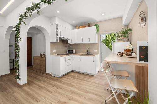 a kitchen with white cabinets and a table and chairs at Stylish & Sleek Flat near the Beach by HostWise in Armação de Pêra