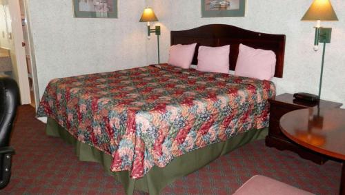 a hotel room with a bed with a colorful comforter at Magnuson Hotel Fowlerville in Fowlerville
