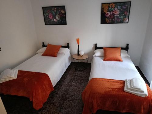 a bedroom with two beds with orange and white sheets at Casa el moral 2 in Castillejo de Martín Viejo