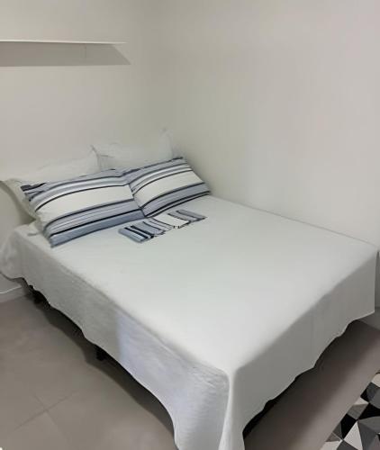 a white bed with pillows on it in a room at Cantinho Charmoso Pertinho do Mar in Navegantes