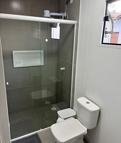 a bathroom with a toilet and a glass shower at Cantinho Charmoso Pertinho do Mar in Navegantes