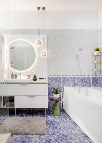 a bathroom with a tub and a sink and a mirror at Riverside Apartman**** Miskolc in Miskolc