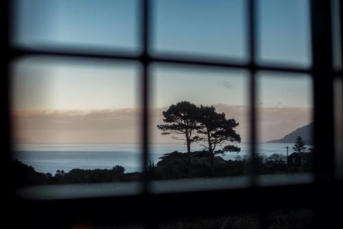 a window with a view of the ocean and a tree at Liiiving in Azores - Ocean View House in Canto da Areia