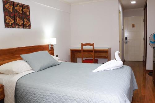 a bedroom with a white bed with a swan on it at Hotel Paola Antofagasta in Antofagasta
