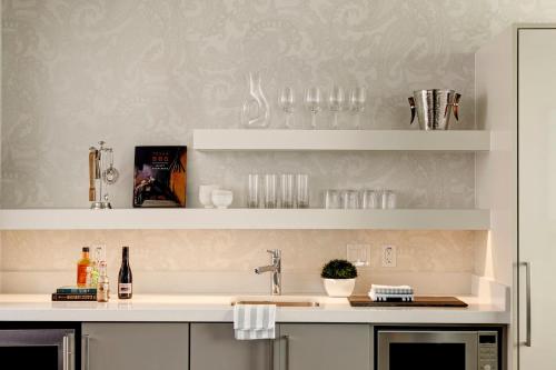 a kitchen with a sink and shelves with wine glasses at Archer Hotel Austin in Austin