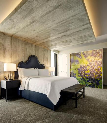 a bedroom with a large bed and a large painting at Archer Hotel Austin in Austin