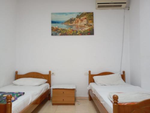 two beds in a room with a painting on the wall at Enjoy Hostel in Tirana