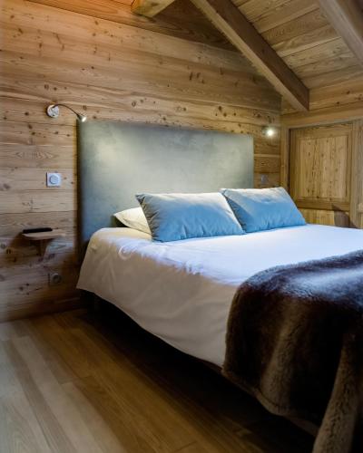 a bedroom with a large bed with wooden walls at CHALET EVEREST Les CHALETS D'HINOUKA SERRE CHEVALIER-CHANTEMERLE 200 m des pistes in Saint-Chaffrey