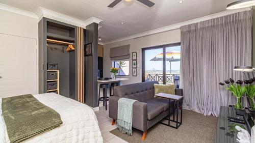 a bedroom with a bed and a desk and a balcony at Studio Bella Vista Plett in Plettenberg Bay