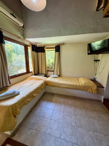 two beds in a room with two windows at Piedra Serrana in San Antonio de Arredondo