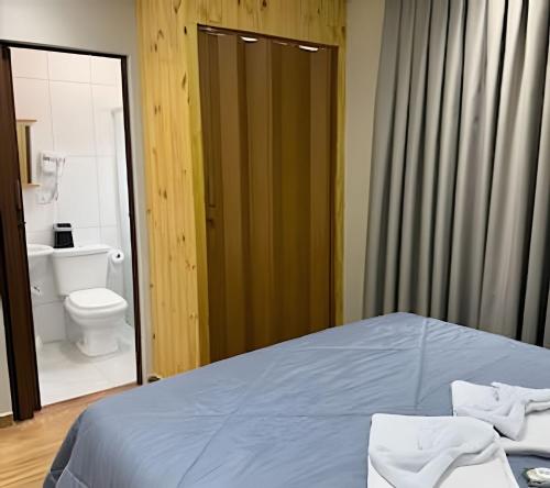 a bedroom with a bed and a bathroom with a toilet at Joseph Prime Studio Hotel Extrema MG in Extrema