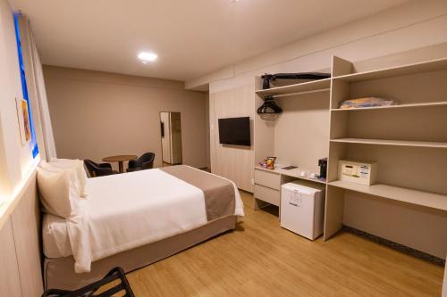 a bedroom with a bed and a desk and shelves at Hotel da Costa By Nobile in Aracaju