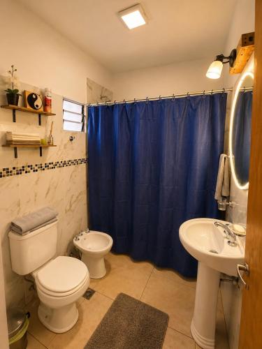 a bathroom with a toilet and a sink with a blue shower curtain at Hospedaje Don Felipe in Belén