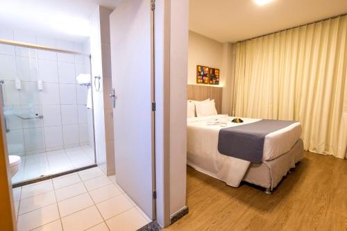 a hotel room with a bed and a shower at Hotel da Costa By Nobile in Aracaju