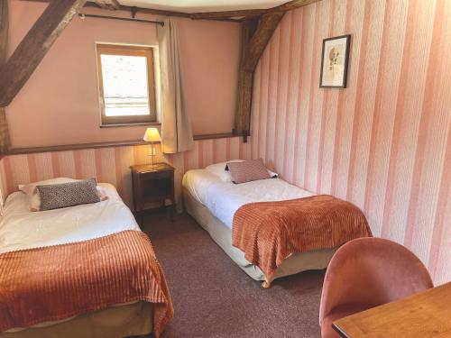 a room with two beds and a table and a window at Hôtel des Cymaises in Semur-en-Auxois