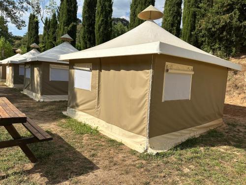 a row of tents in a field with a picnic table at Camping Rio Vero de Alquézar in Alquézar