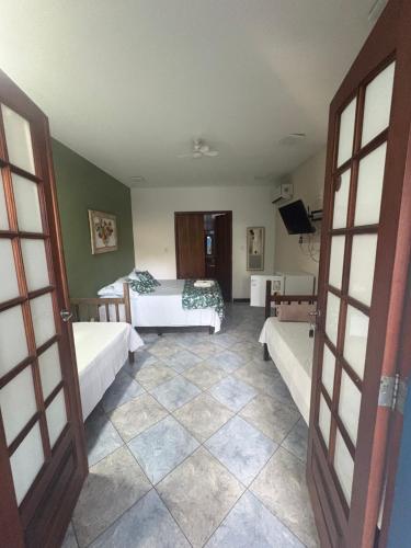 a bedroom with two beds and a tv in it at Pousada Aqui é Para-Ti in Paraty