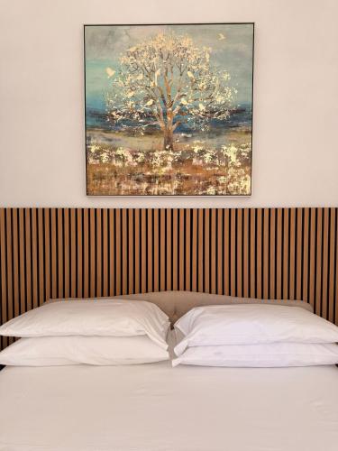 a painting above a bed with two white pillows at Agriturismo Adenzia in Porto Empedocle