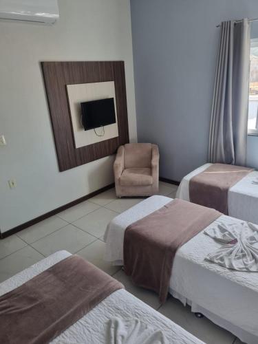 a hotel room with two beds and a chair at Miotto Executive Hotel in Navegantes